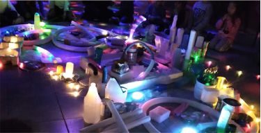 Instalación lúdica nocturna con luces de colores, tubos y velas para un evento de empresa